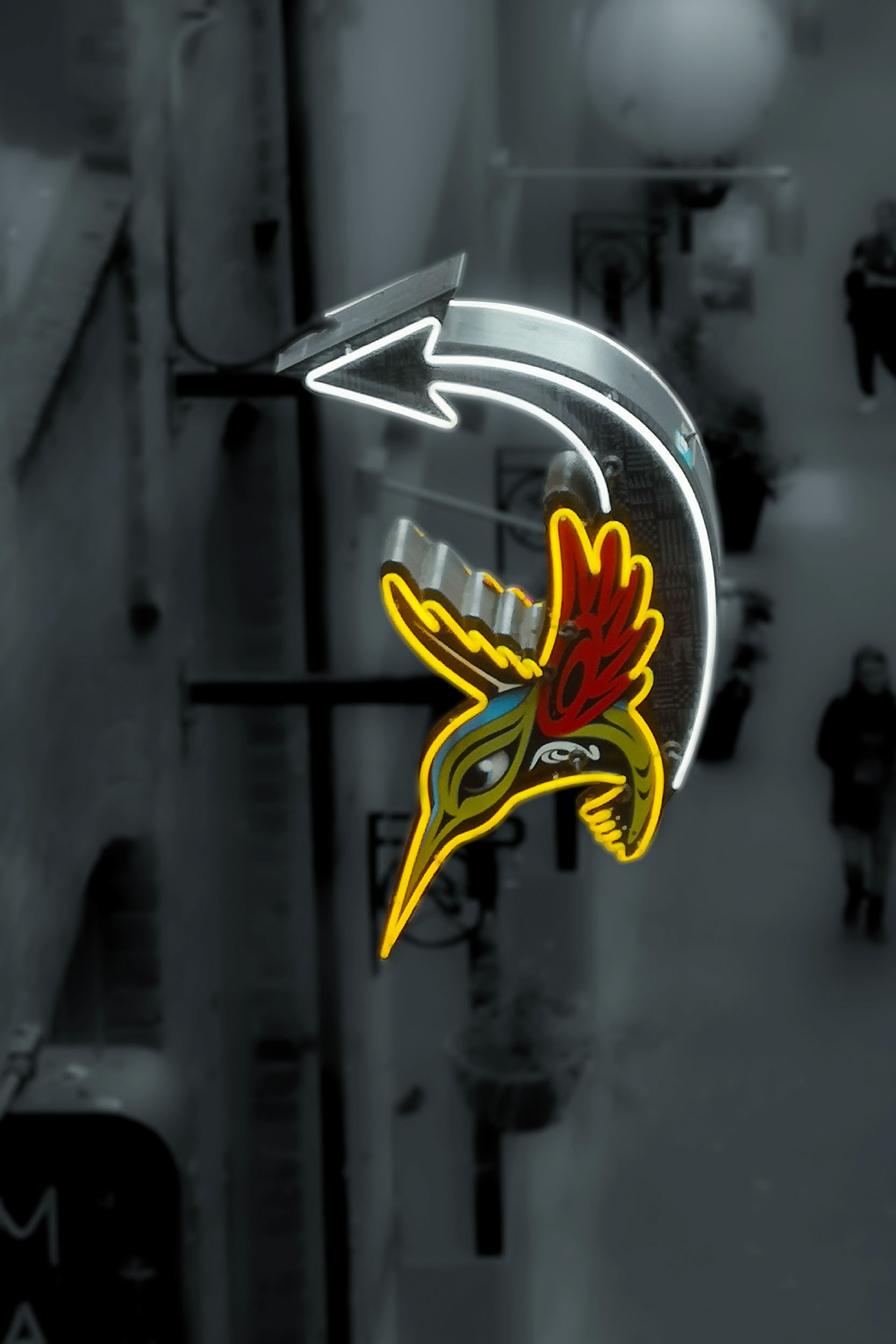 A bright bird motif cuts through a nearly monochrome street scene.