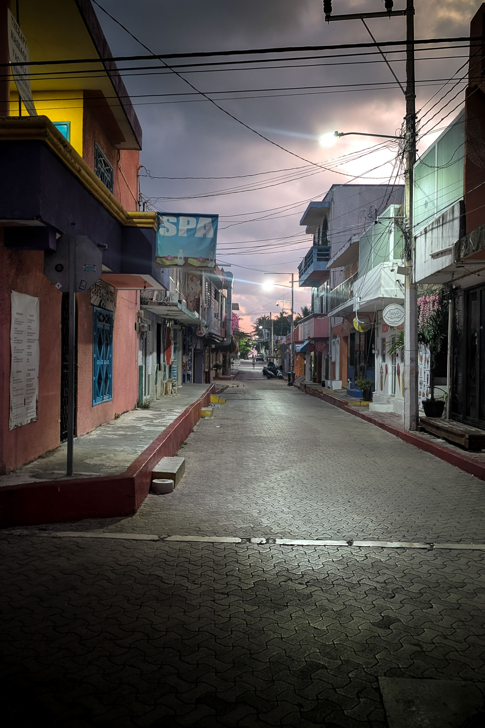A quiet city street holds the softened light and wet surface of recent rain.